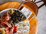 A platter of seafood like lobster and oysters on a wooden table.